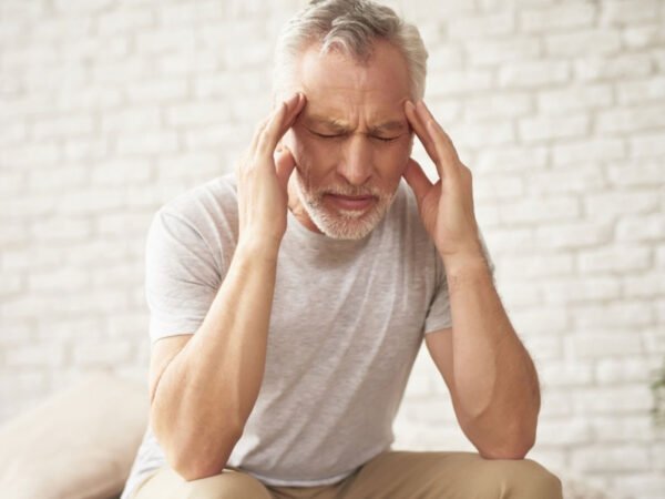 Andropoz (geç başlangıçlı hipogonadizm) sürecinde testosteron düşüşünü, yorgunluk–libido azalması–ereksiyon sorunları–kas kaybı ve ruh hâli değişikliklerini gösteren tıbbi illüstrasyon.