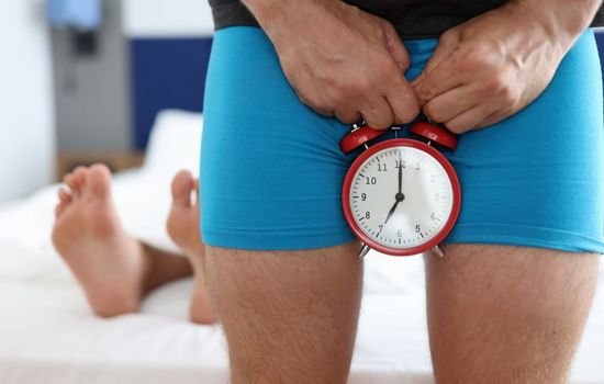 Erkeklerde iktidarsızlık sorununu sembolize eden alarm saati tutan erkek görseli.